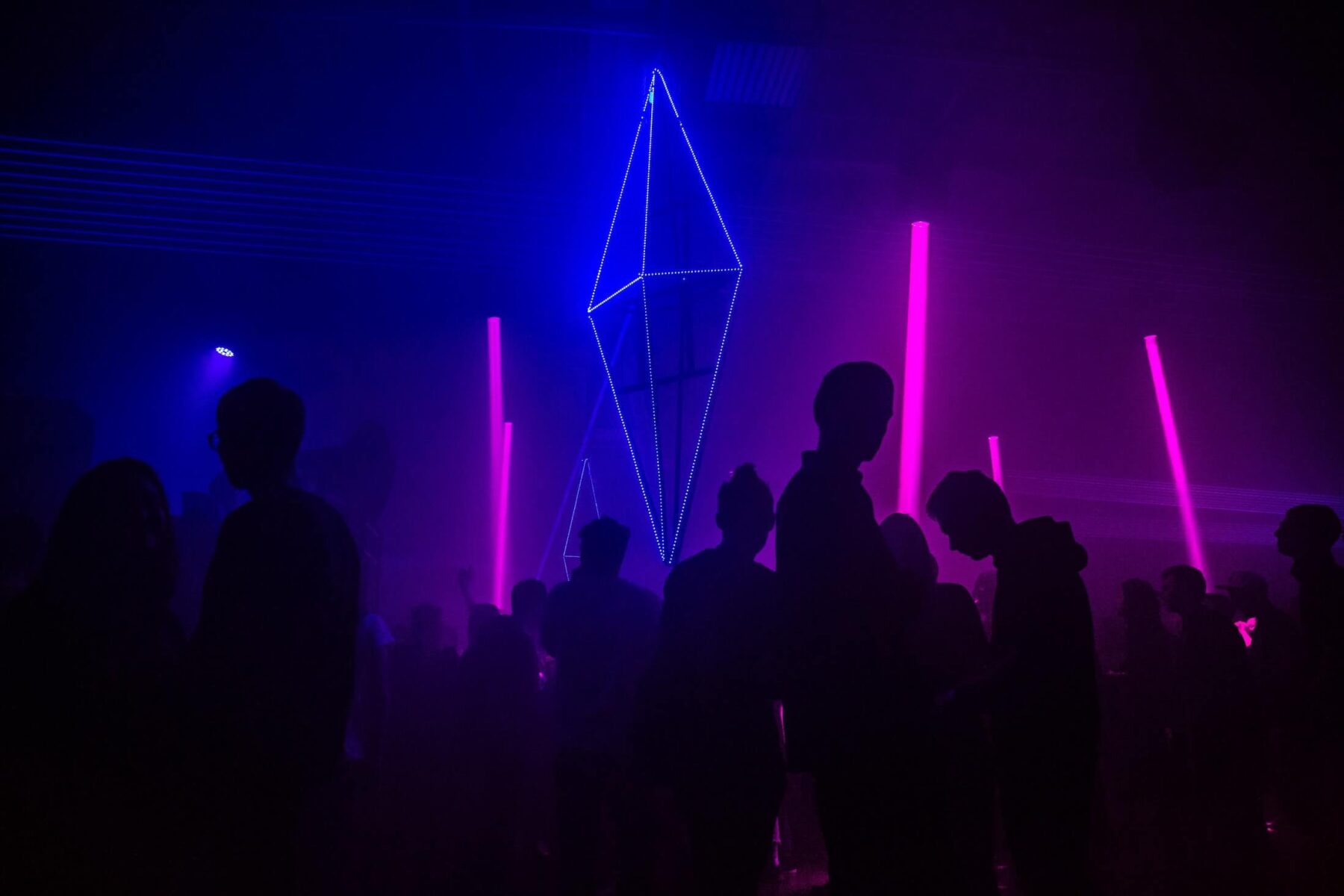 A group of people standing in front of a neon sign.